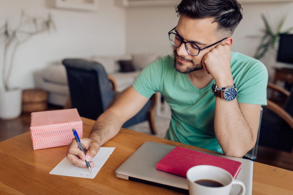 man writing note at desk love letter for her