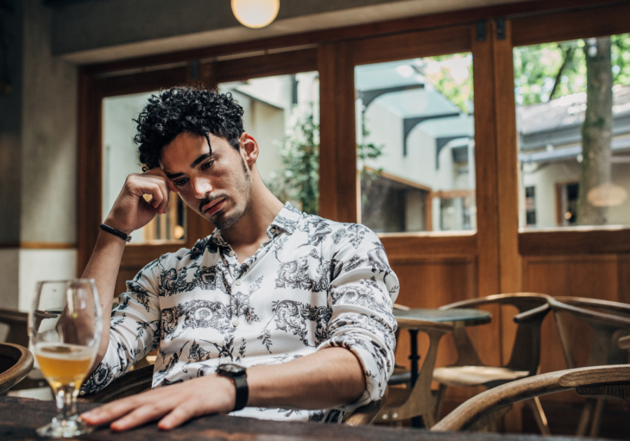 man looking sad with a glass of beer signs he's hurting after the break up