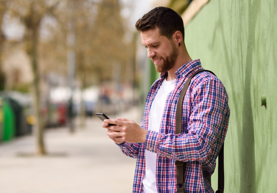 man standing on the sidewalk using phone anniversary messages to your boyfriend