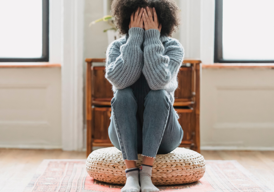 woman sitting covering face Signs You Are Unattractive