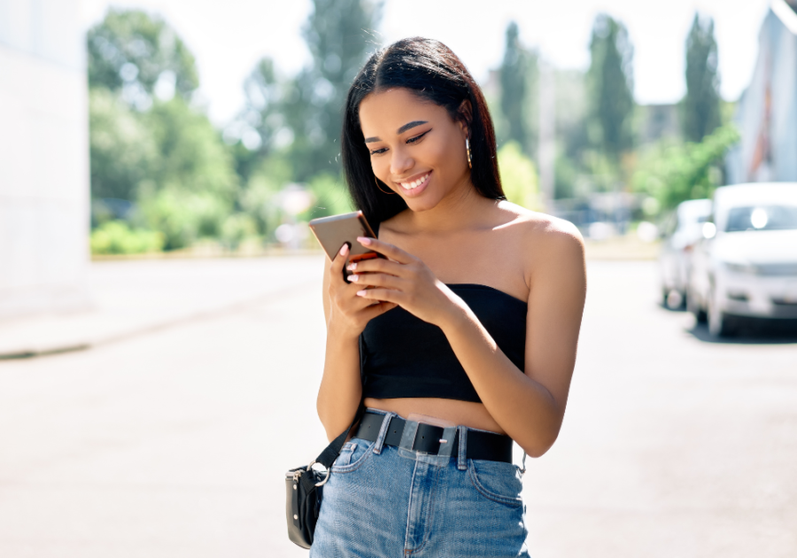 young woman smiling looking at phone How to Respond to 'I Miss You'