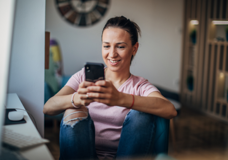 woman smiling looking at phone How to Respond to 'I Miss You'