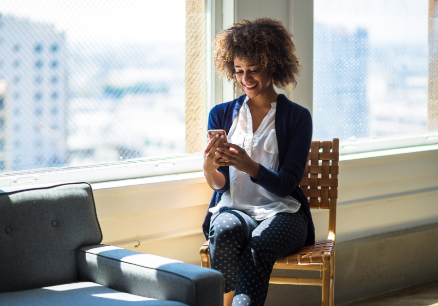 woman sitting on chair looking at phone Angel Number 555