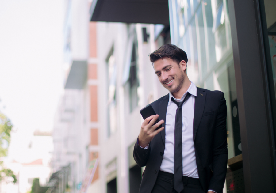 man smiling looking at phone How to Respond to 'I Miss You'