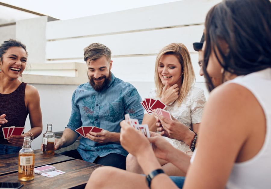 group playing cards around outdoor table Drinking Games for Couples