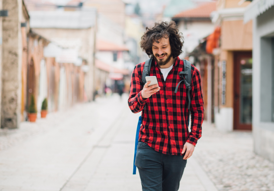 man walking smiling looking at phone start a conversation on Tinder