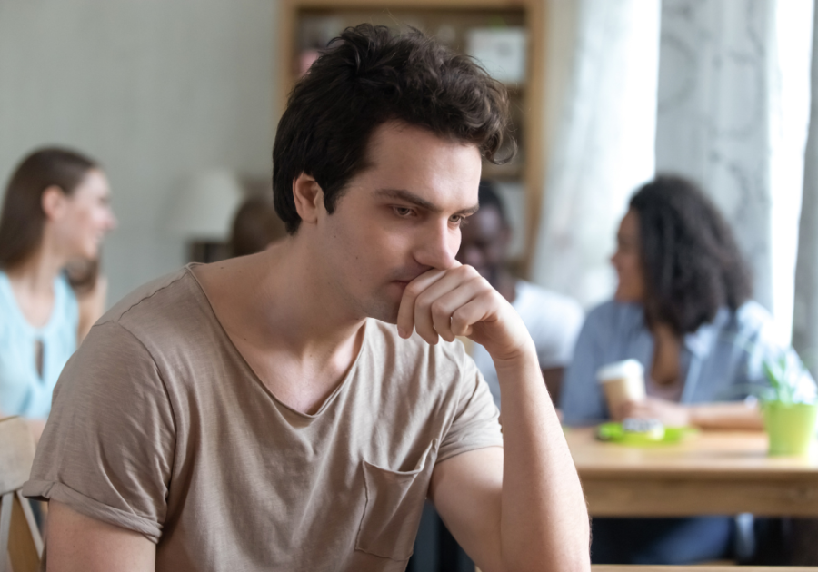 man sitting alone dejected in coffee shop why am I so hard on myself