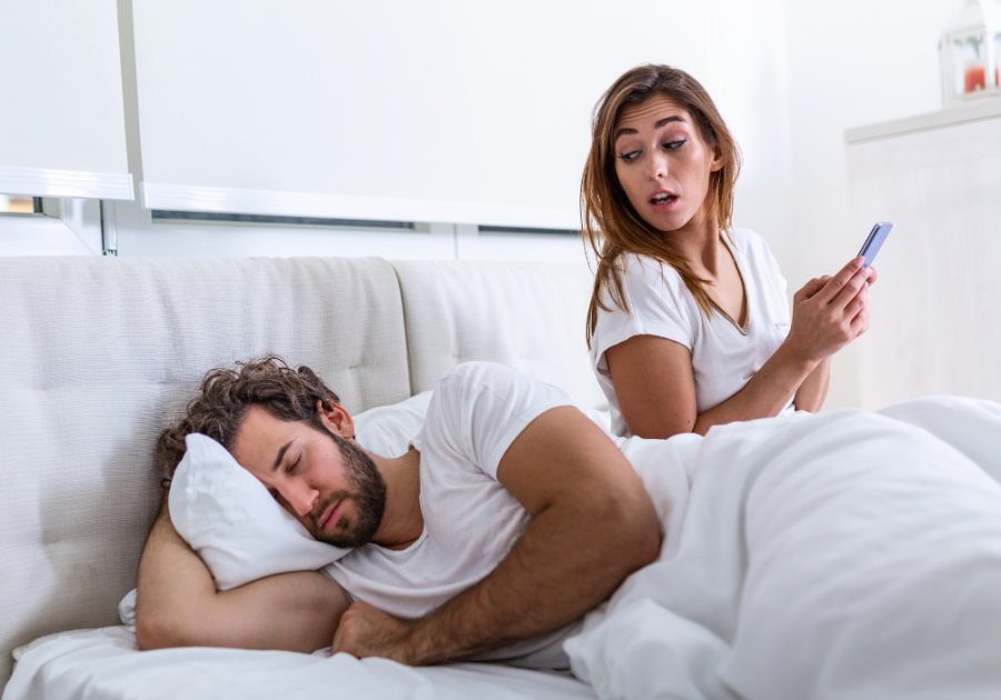 woman on phone while man is sleeping trick questions to ask your girlfriend to see if she's cheating