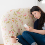 woman sitting alone looking at phone How Long Does a Crush Last?