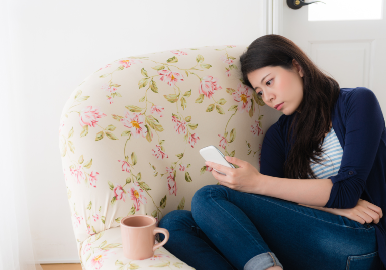 woman sitting alone looking at phone How Long Does a Crush Last?