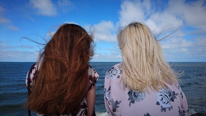 two women sitting at ocean talking best friend tag