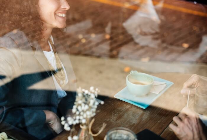 woman sitting in coffee smiling at date first date questions