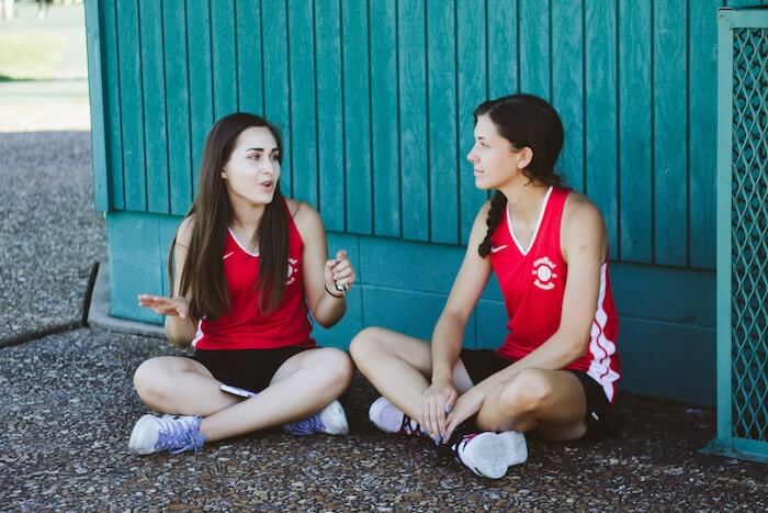 women sitting on ground talking Questions to Ask Your Best Friend