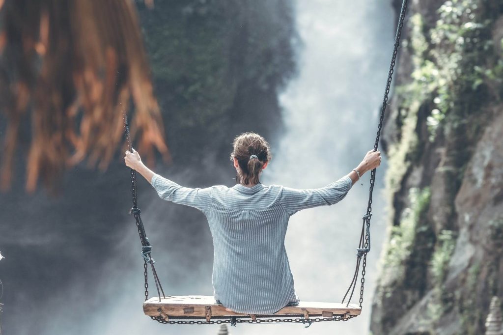 women sitting on swing at waterfall relaxing things to do