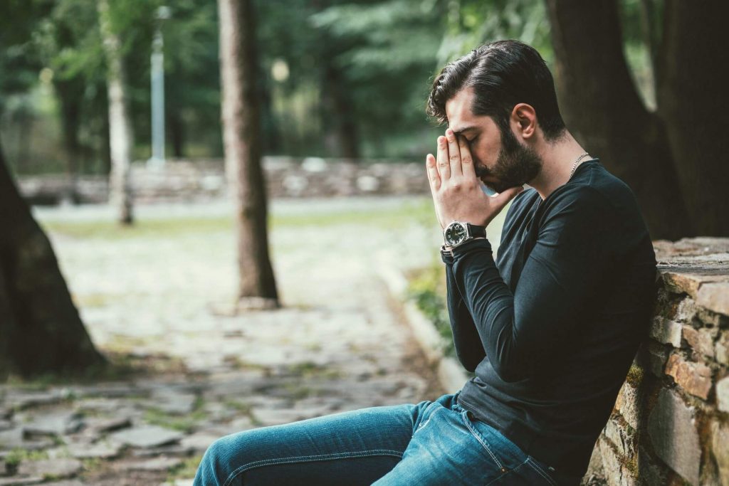 man sitting on bench covering face Signs You Have a Bad Attitude 