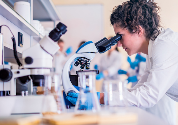 woman looking in microscope in lab Smartest Personality Types