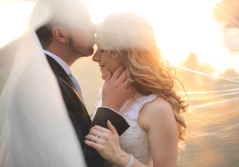 Close-up picture of newlyweds husband kissing forehead of wife letter to husband on wedding day