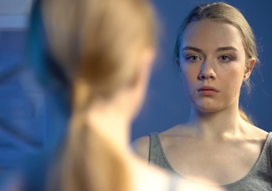 blonde woman looking at the mirror signs of an insecure woman