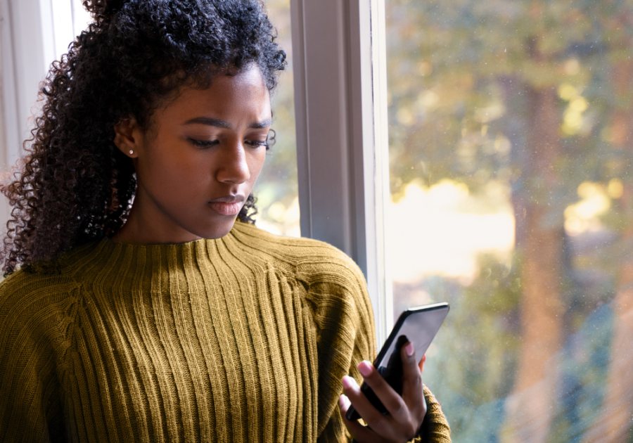 woman standing by the window looking through phone how to respond to a breakup text