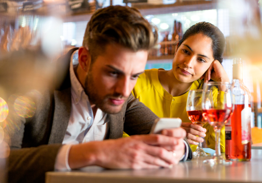 man busy with phone while woman is looking at him signs of a weak man in a relationship