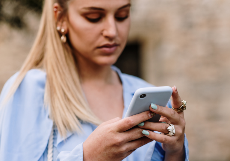 blonde girl using phone should I text my ex