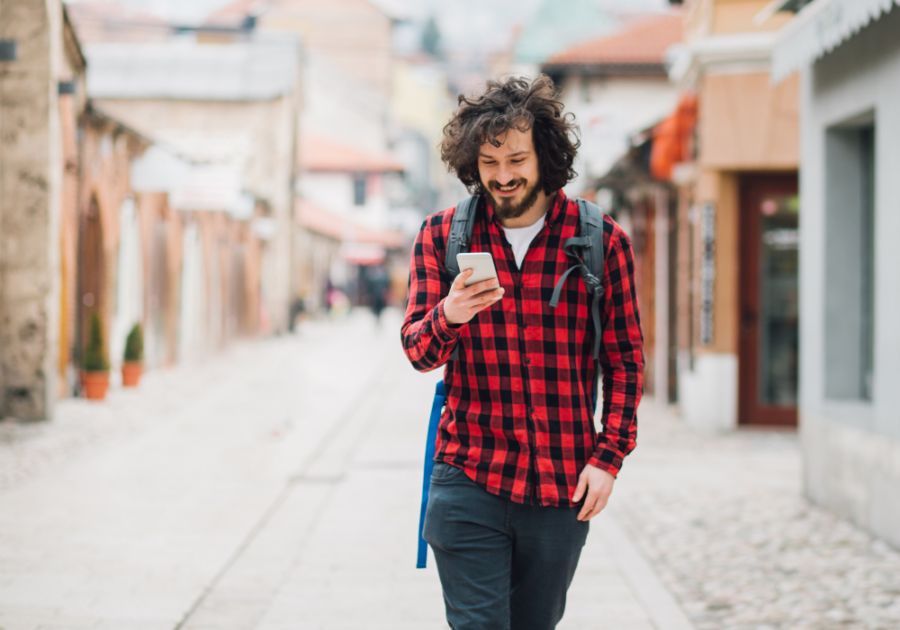 man walking smiling while looking at phone deep things to say to your boyfriend over text