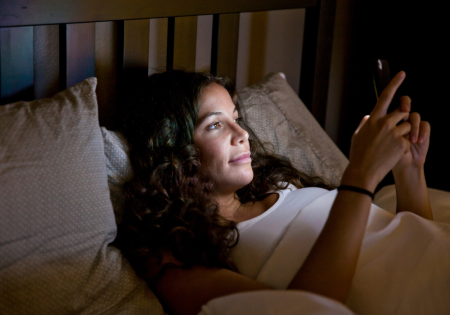 woman lying in bed using phone deep things to say to your boyfriend over text