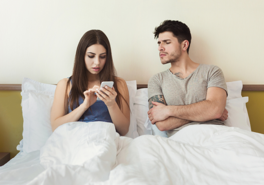 wife texting while sitting down in bed with husband psychological effects of false allegations in a relationship