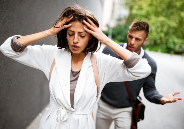 woman holding head while man follows her feeling trapped in a relationship