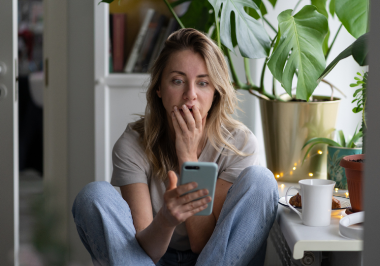 woman looking at phone while covering mouth with hand when stop reaching out to a friend