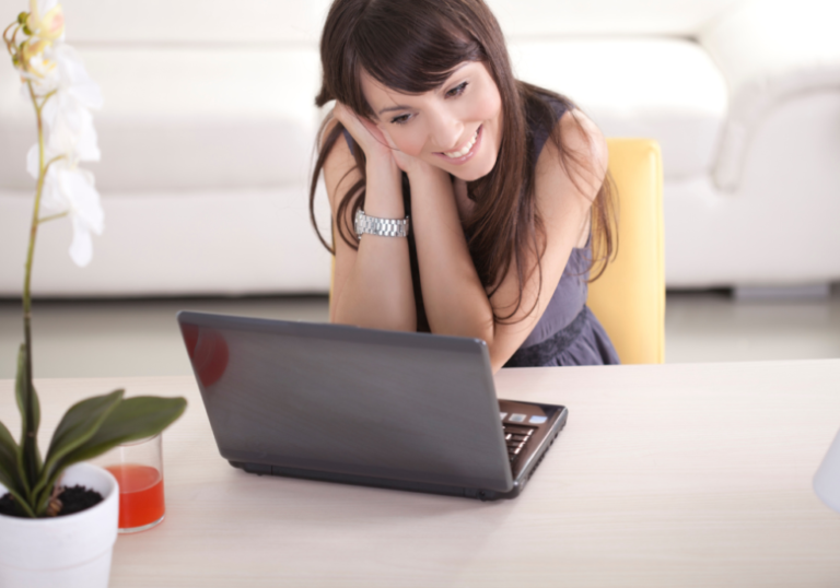 woman smiling in front of her laptop online dating questions to ask him