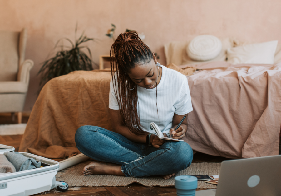 woman sitting on the floor writing in a notebook love letter for long distance boyfriend