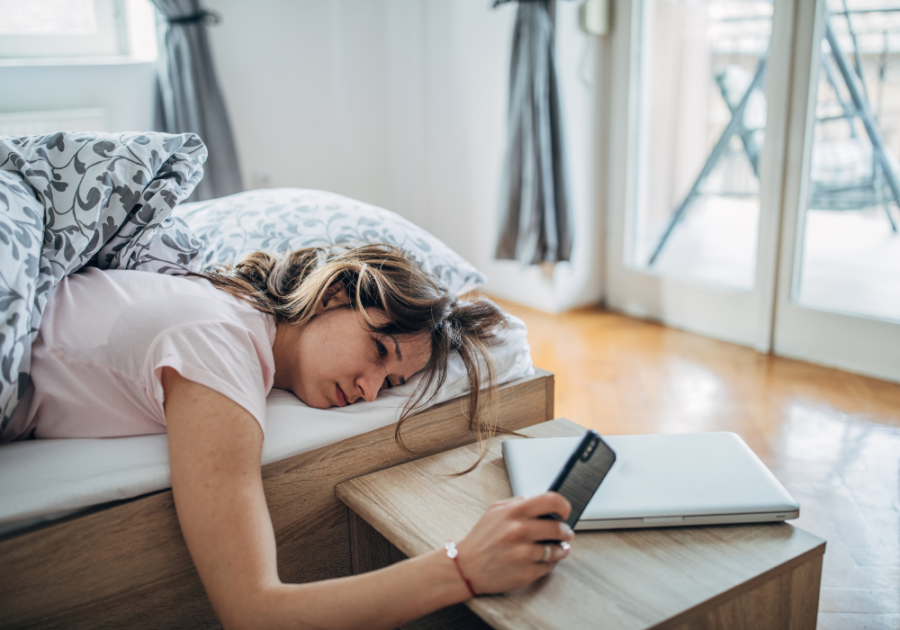 woman in bed checking phone why is he not texting me