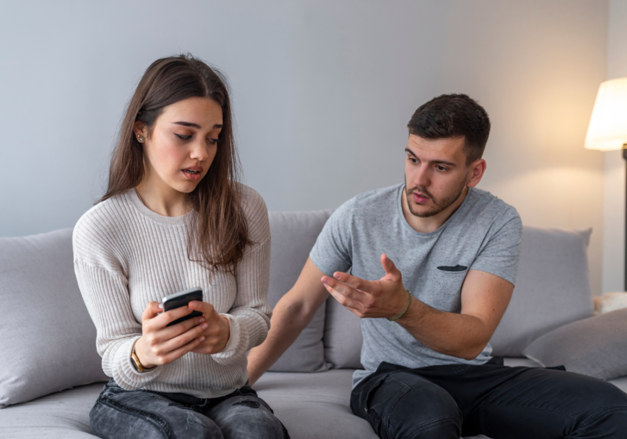 woman holding phone slightly leaning away from boyfriend in a long-term relationship but have feelings for someone else