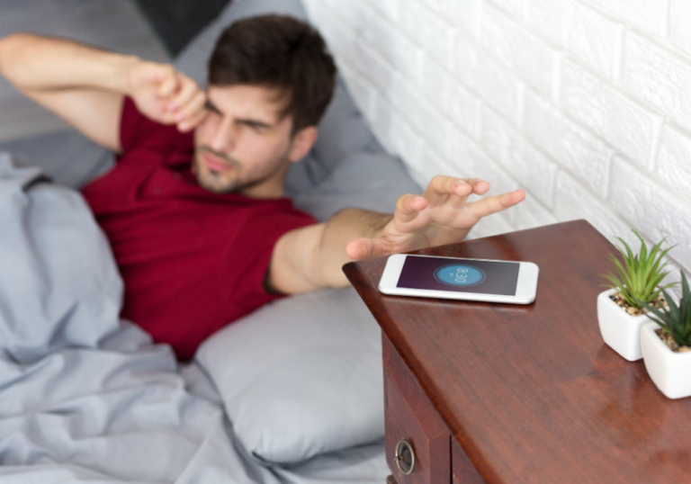 man reaching for his phone after waking up good morning text to your crush