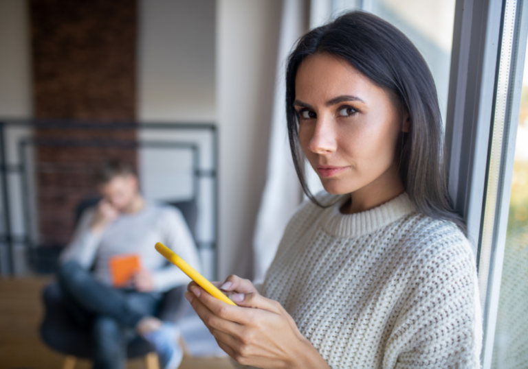 woman holding phone looking at the camera gut feeling he's cheating no proof