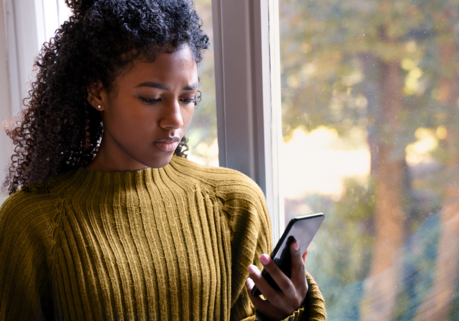 woman standing by the window looking at phone can a man sleep with a woman without developing feeling