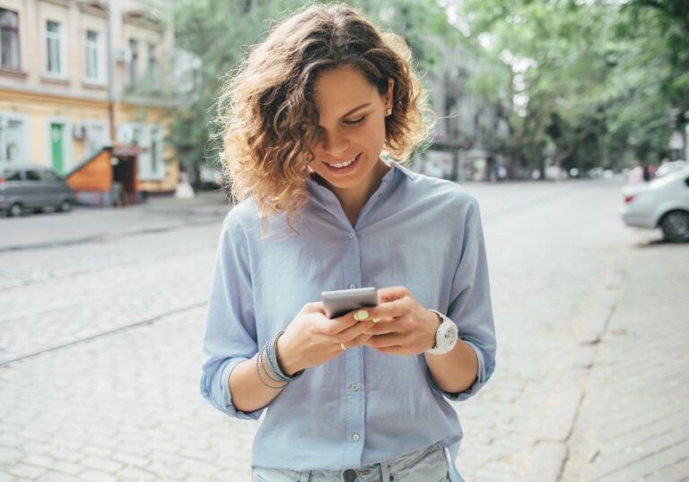 woman outside with phone smiling Good Morning Paragraphs for Her to Make Her Smile