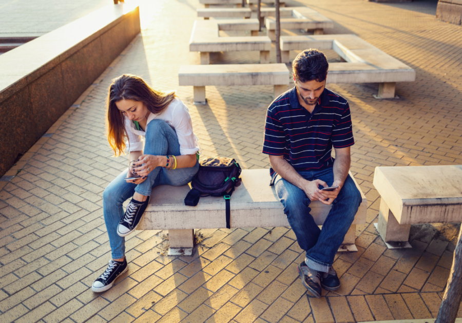 man and woman sitting in a bench using their own phones Why is he ignoring me all of a sudden