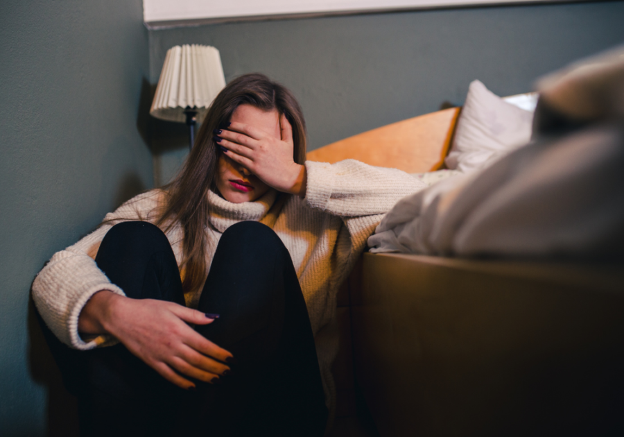 woman covering her eyes while sitting on the floor emotionally depleted from living with a narcissist