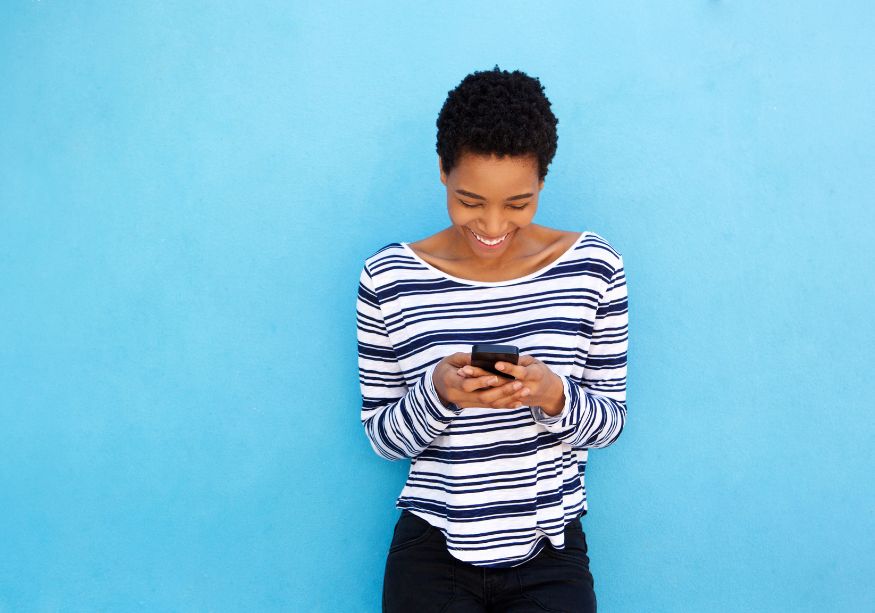 woman at blue wall smiling looking at phone Good Morning Paragraphs for Her to Make Her Smile