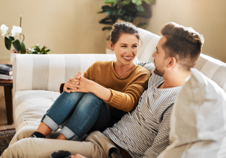 couple sitting on sofa smiling Qualities Of A Good Wife