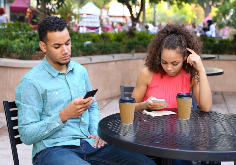 couple sitting outside both looking at their phones not talking dating red flags