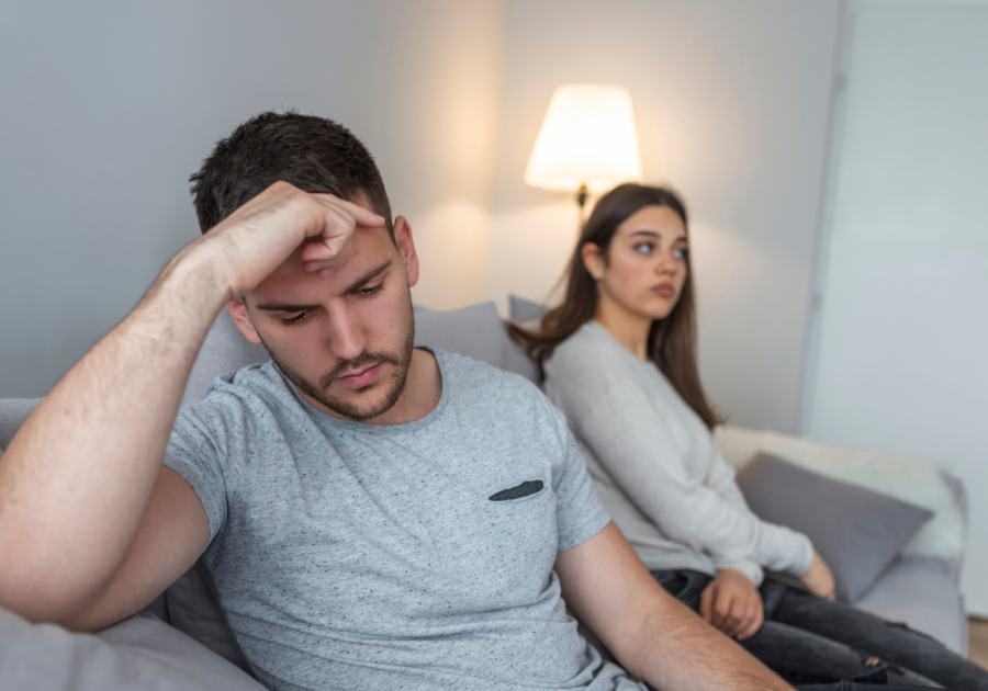 couple sitting on sofa emotions Signs He's Pretending To Love You