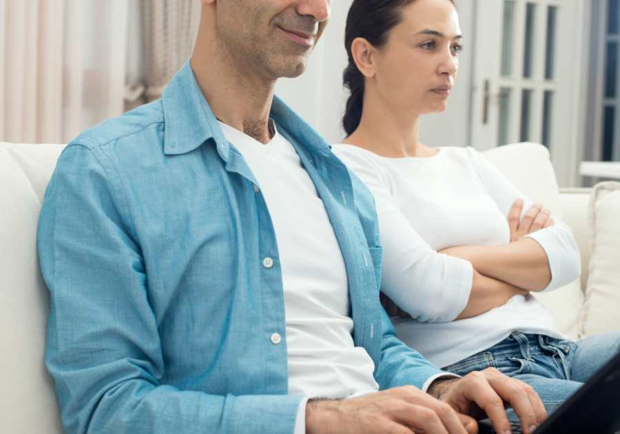 couple sitting on sofa man on computer signs he's pretending to love you