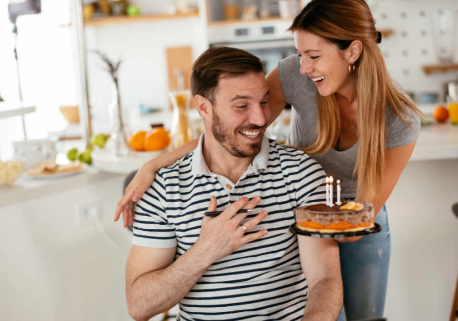 woman offering cake with candles birthday letters for husband