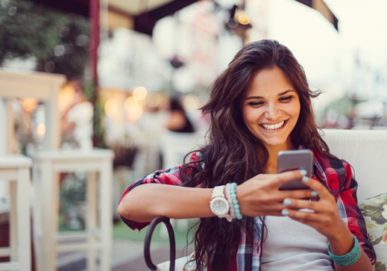 woman smiling looking at phone Hinge 'Dating Me Is Like' Prompt