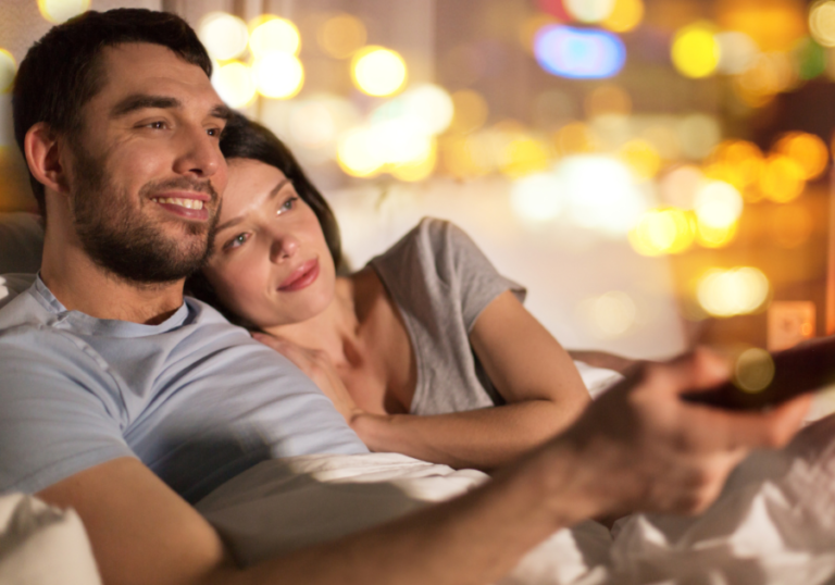 young couple sitting on sofa watching tv movies like the notebook