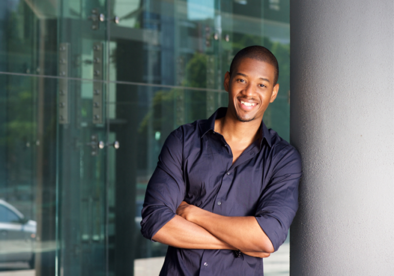 Man standing by pillar smiling High-Value Man traits