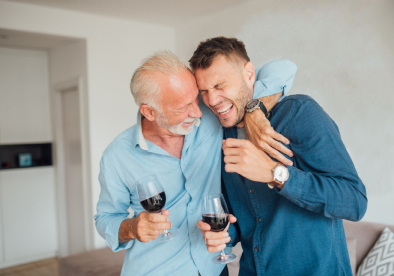 older man laughing with arm around young man Questions To Ask Your Dad